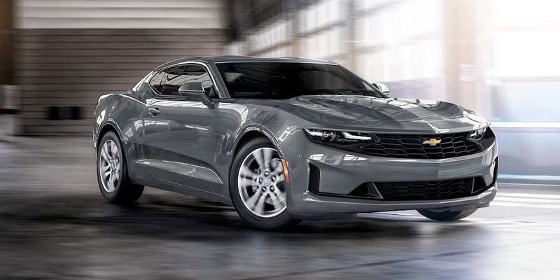 A silver Chevrolet Camaro driving inside a modern industrial-style building
