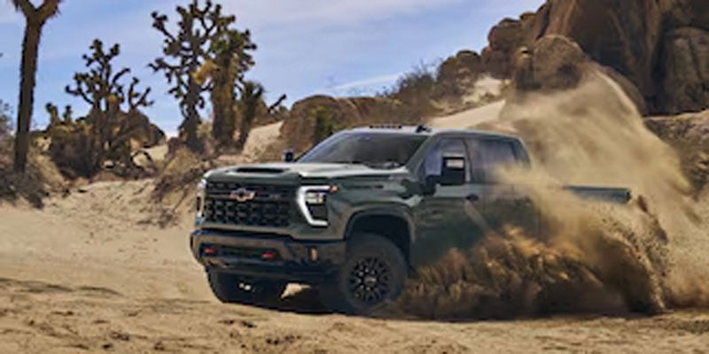 A Chevrolet Silverado 2500 HD driving through a sandy desert landscape