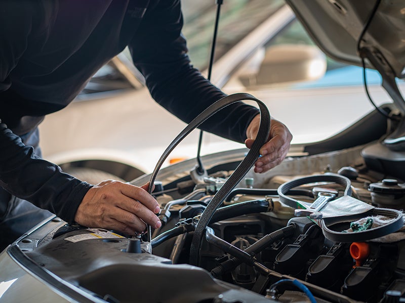 A technician working under the hood of a vehicle